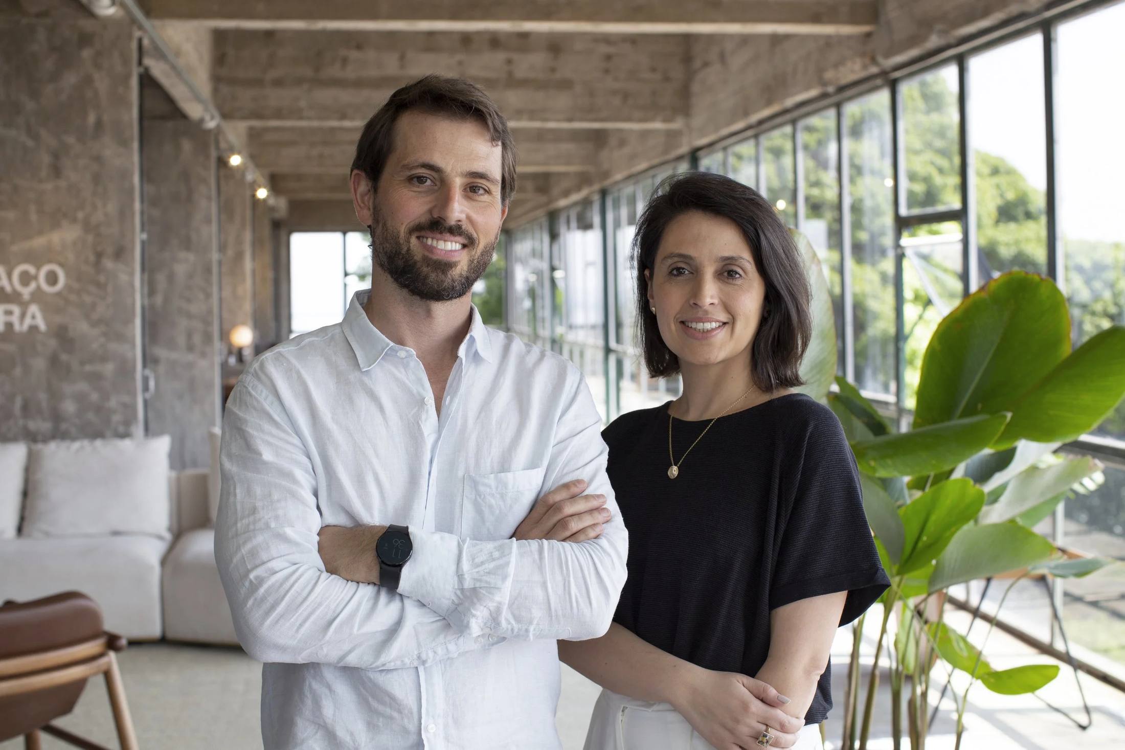 Ricardo Dias Michelon e Juliana Schnor, sócios da Sopra, em um ambiente com plantas e janelas amplas